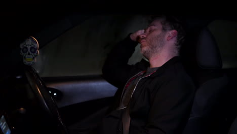 a man sleeping in his car at n ight next to a busy road in a city