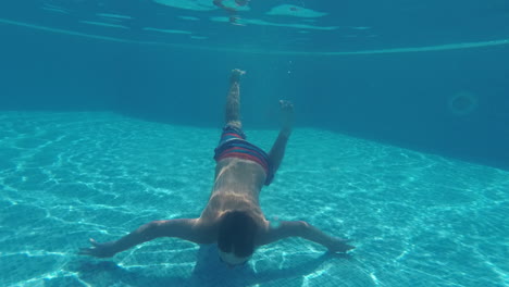 child swimming underwater in the pool