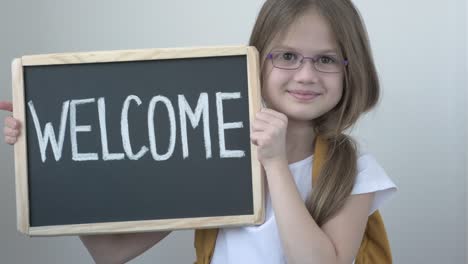 niña con gafas y mochila con una inscripción de bienvenida en la pizarra. de vuelta a la escuela