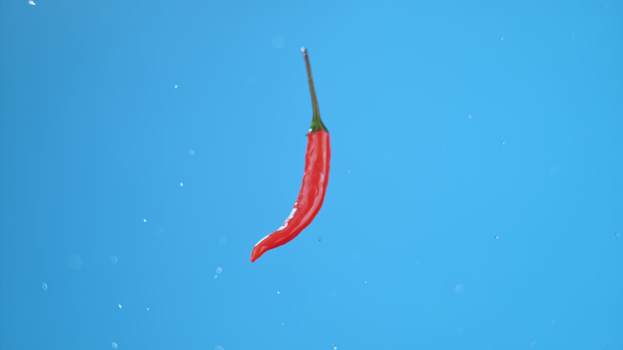 단 하나의 작은 뜨거운 은 고추가 공중에 날아다니며 작은 물방울로 회전합니다.