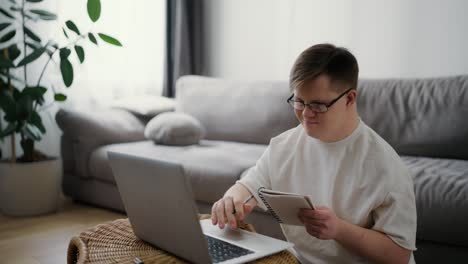 Down-syndrome-adult-man-sitting-at-home,-using-laptop-for-learning