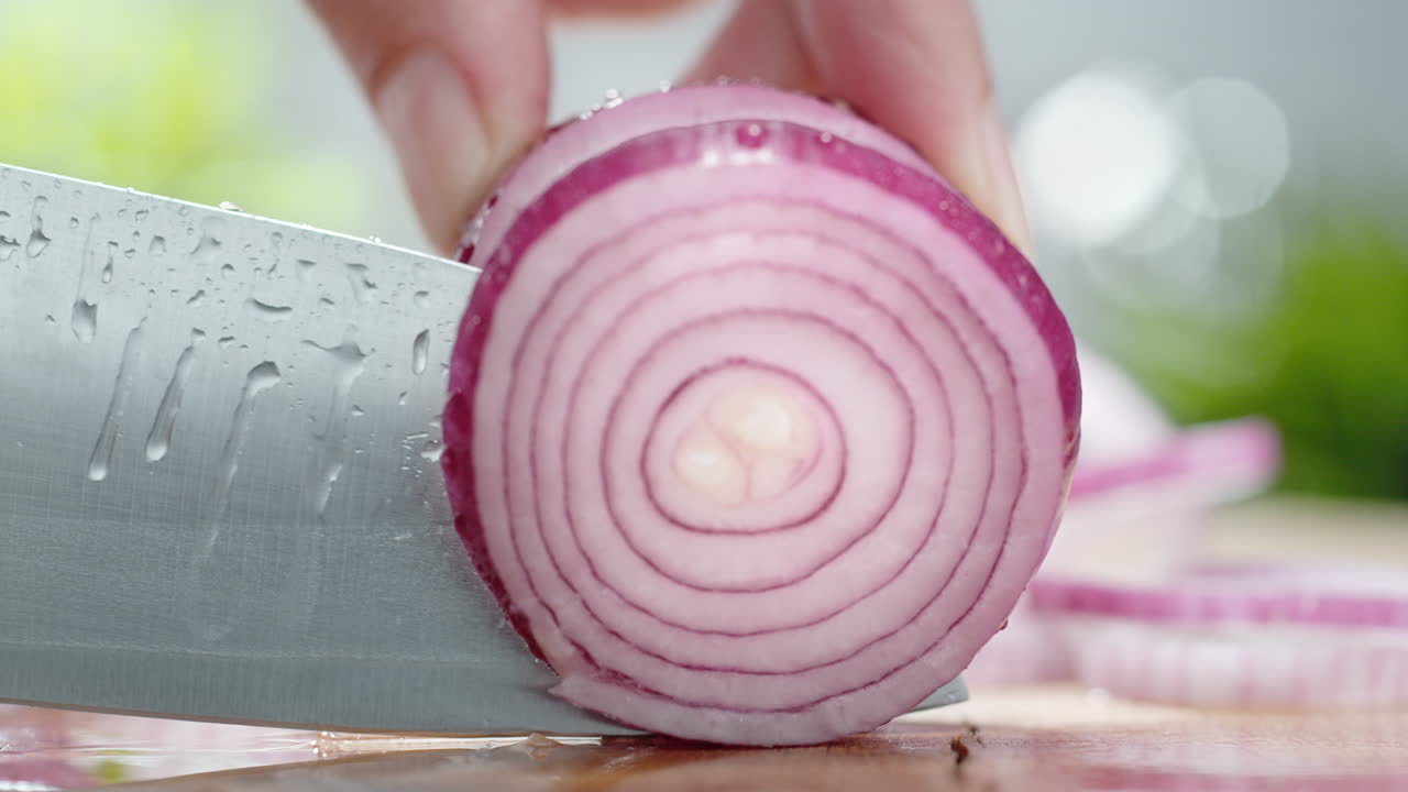 Cutting Red Onion With A Sharp Knife On A Wooden Water Covered Cutting Board in Macro and Slow Motion