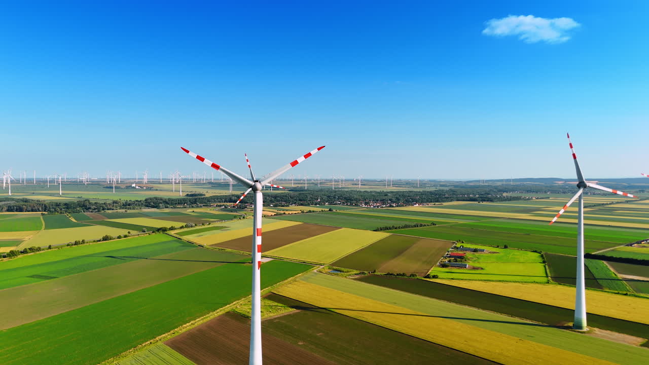 Tall wind turbines in fields. Wind turbines rotate peacefully in an expansive green landscape under a clear blue sky