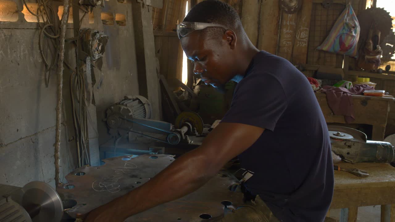 Black African Male Model Works inside a Metallic Saw Factory Sharpening Tools