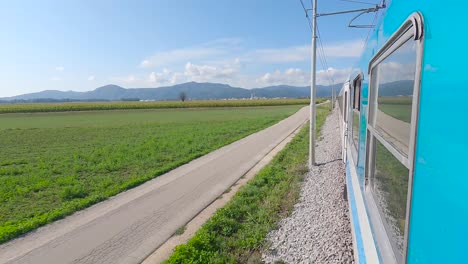 Passenger-train-in-Slovenia-leaving-Ljubljana-among-fields,-onboard-camera