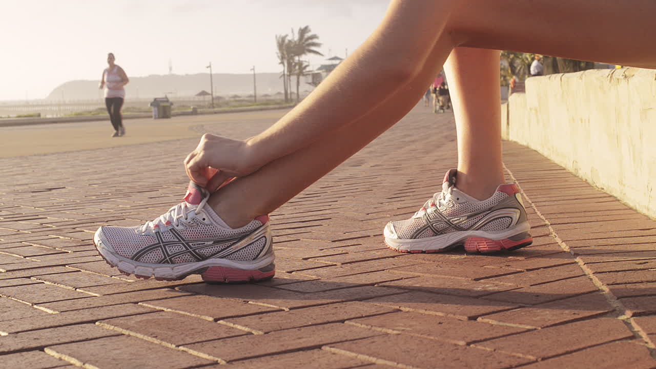 Donna runner che si allaccia i lacci delle scarpe mentre si esercita all'aperto.