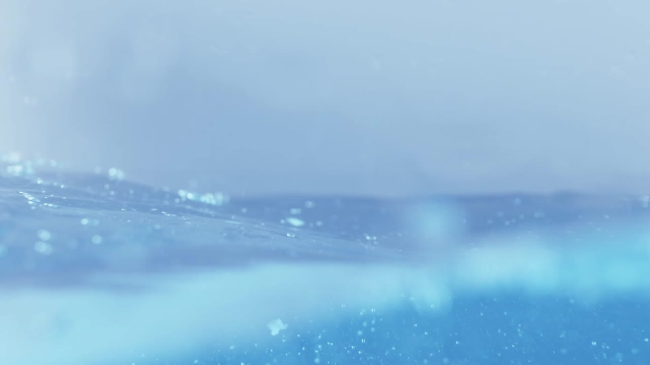 슬로우 모션의 깨끗한 물 표면은 물이 튀는 상점으로 화면을 채우고 기포로 액체 표면을 흔들고 있습니다.