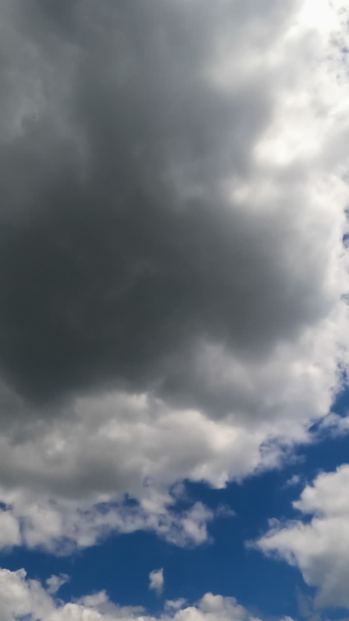 Cloudscape building in the blue sky. Soft puffy clouds flying quickly. Low angle perspective. Timelapse. Vertical video