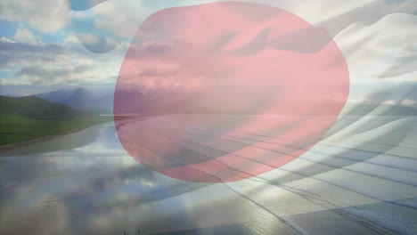 composición digital de la bandera de japón ondeando contra la vista aérea de la playa y las olas del mar