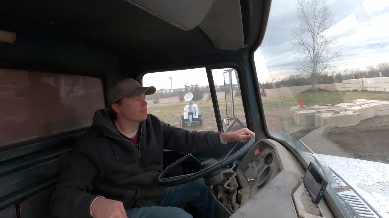 hombre dentro de un camión volquete de 1972 conduciendo hacia un sitio de construcción