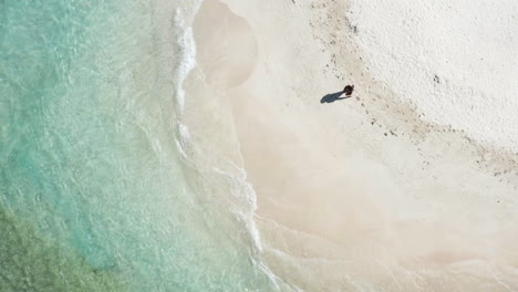 aerial - single woman tourist wearing sarong strolls on beach during summer vacation, near puerto plata