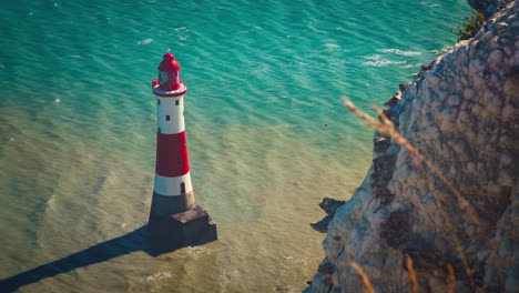cinemagraph of waves moving around red and white beachy head lighthouse near seven sisters cliffs