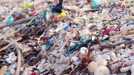 Close-up-Rack-focus-of-trash-littered-on-tropical-beach-on-summer-day