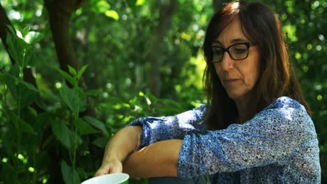 mujer madura tomando café en el jardín 4k