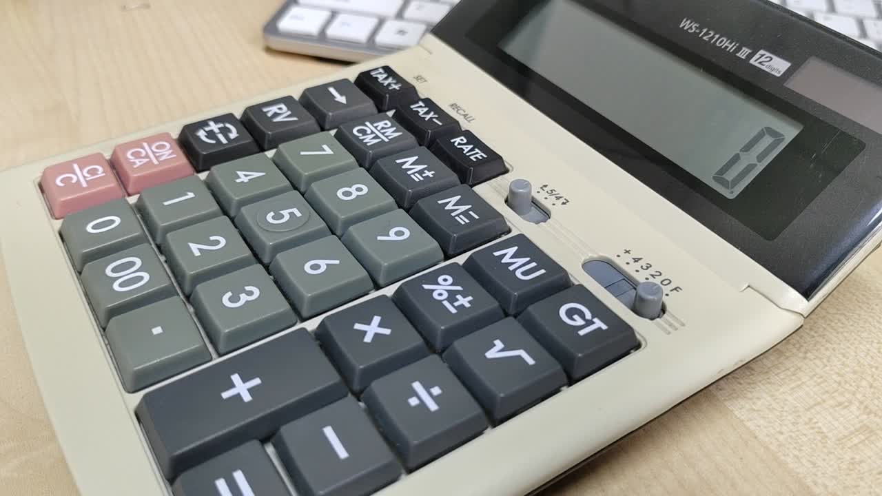 A well-worn, large calculator sits close-up on a desk. Its faded appearance shows frequent use, a testament to countless computations.