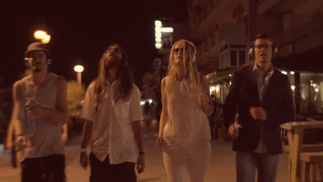 friends in headphones dancing with music during night walk