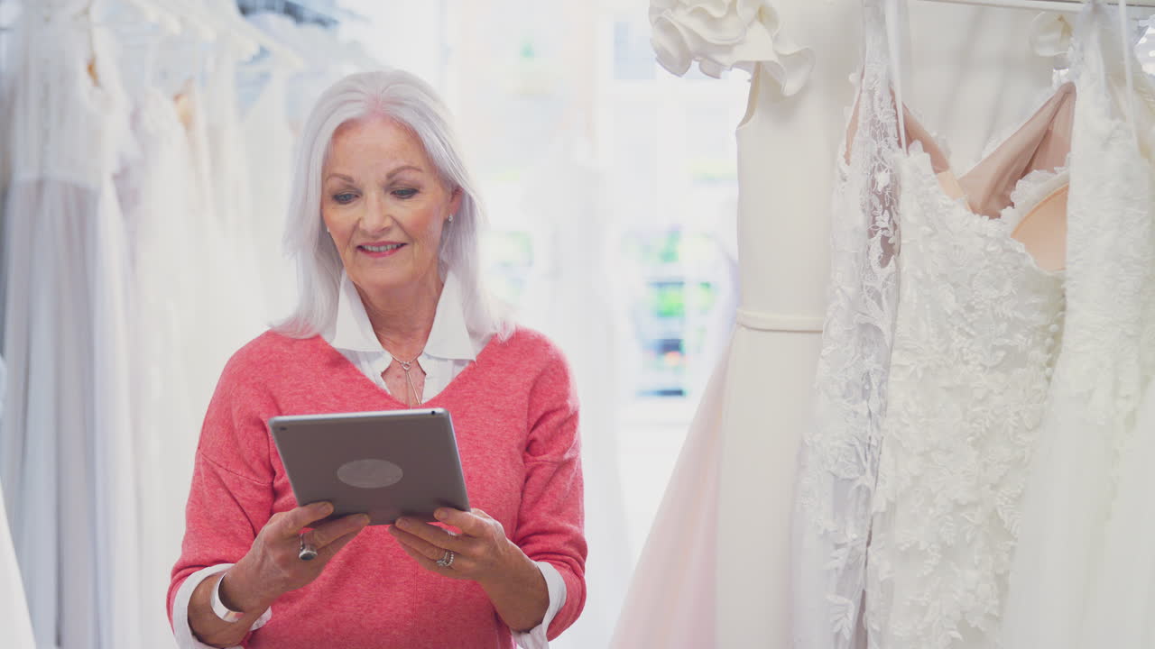 Senior Female Owner Of Bridal Wedding Dress Shop With Digital Tablet