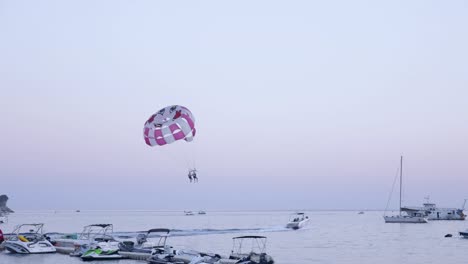 couple parasailing at the sea, boat tows parachute