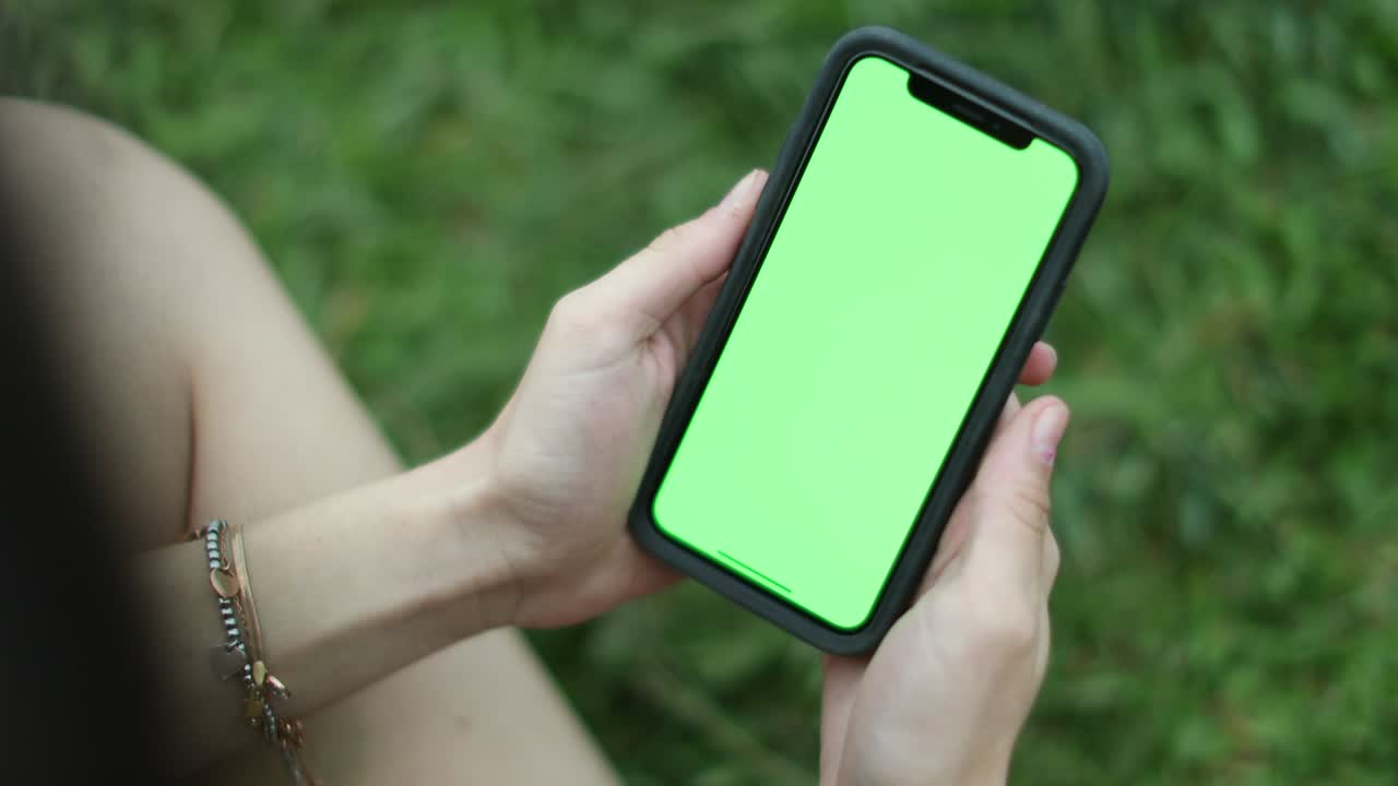 primer plano de las manos de la niña sosteniendo un teléfono inteligente con pantalla verde