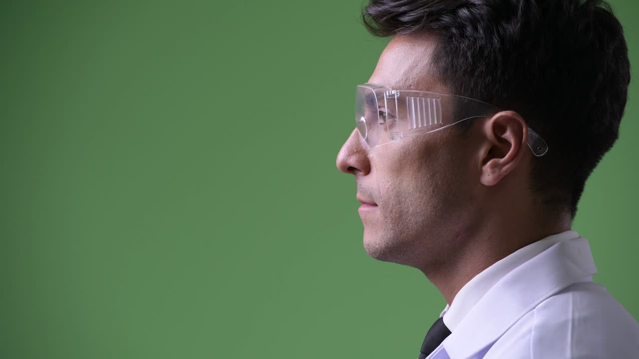 Giovane e affascinante medico ispanico su sfondo verde.
