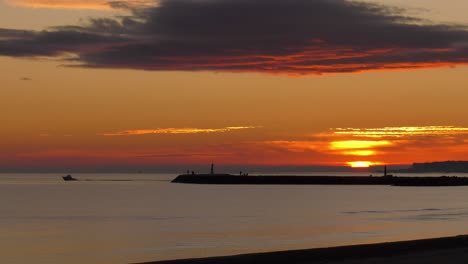 Sun-rising-over-sea-as-boat-leaves-harbor