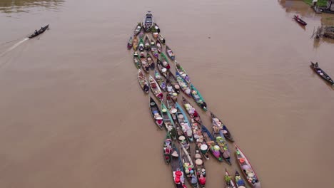 motorboat pulling along traditional floating market boats lok baintan, aerial