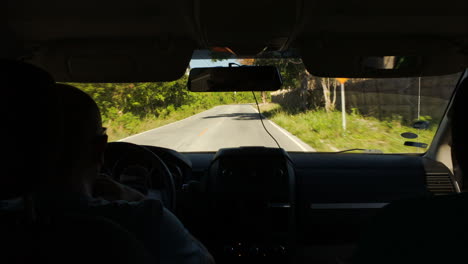 Driving-a-car-on-rural-road-with-many-green-trees-around