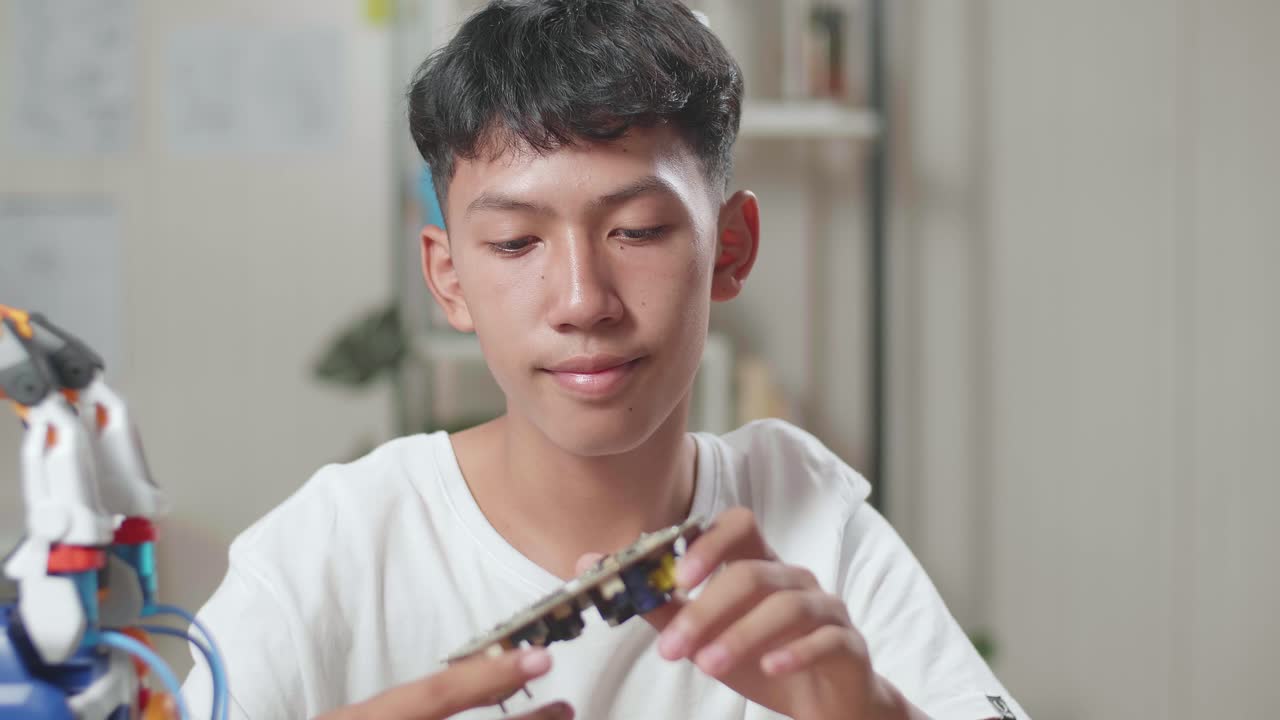 집에서 사이보그 손을 수리하는 동안 회로판을 들고 있는 아시아 소년의 클로즈업