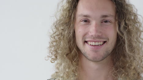 Retrato-De-Un-Joven-Atractivo-Sonriendo-Confiado-Mirando-La-Cámara-Disfrutando-Del-éxito-Expresión-De-Satisfacción-Varón-Caucásico-Peinado-Largo-Rubio-Fondo-Blanco