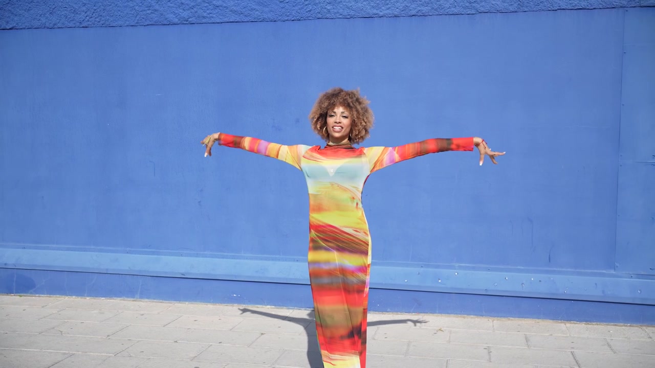 Un ritratto vivace su una parete blu che mette in mostra moda e stile colorato in modo dinamico.