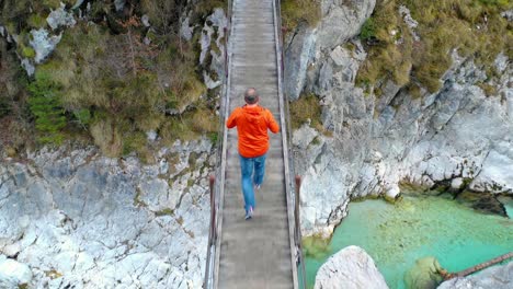 un excursionista caminando sobre un puente de cuerda sobre el río soca, parque nacional triglavski, eslovenia