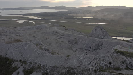 Fly-over-the-mountain-with-abandoned-quarry-on-its-summit-on-the-sunset,-Russia