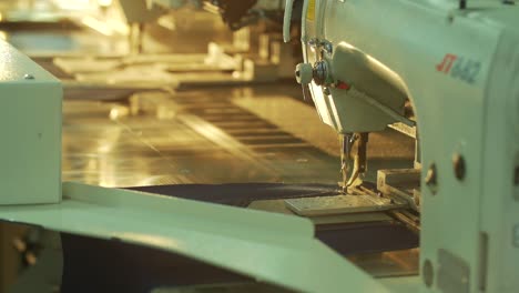 the sewing machine sews a pocket on jeans in the jeans sewing workshop