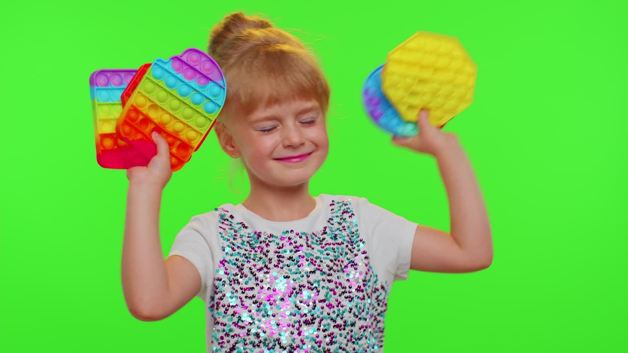 Niña pequeña y bonita mostrando juguetes sensoriales pop-it de burbujas de silicona blandas