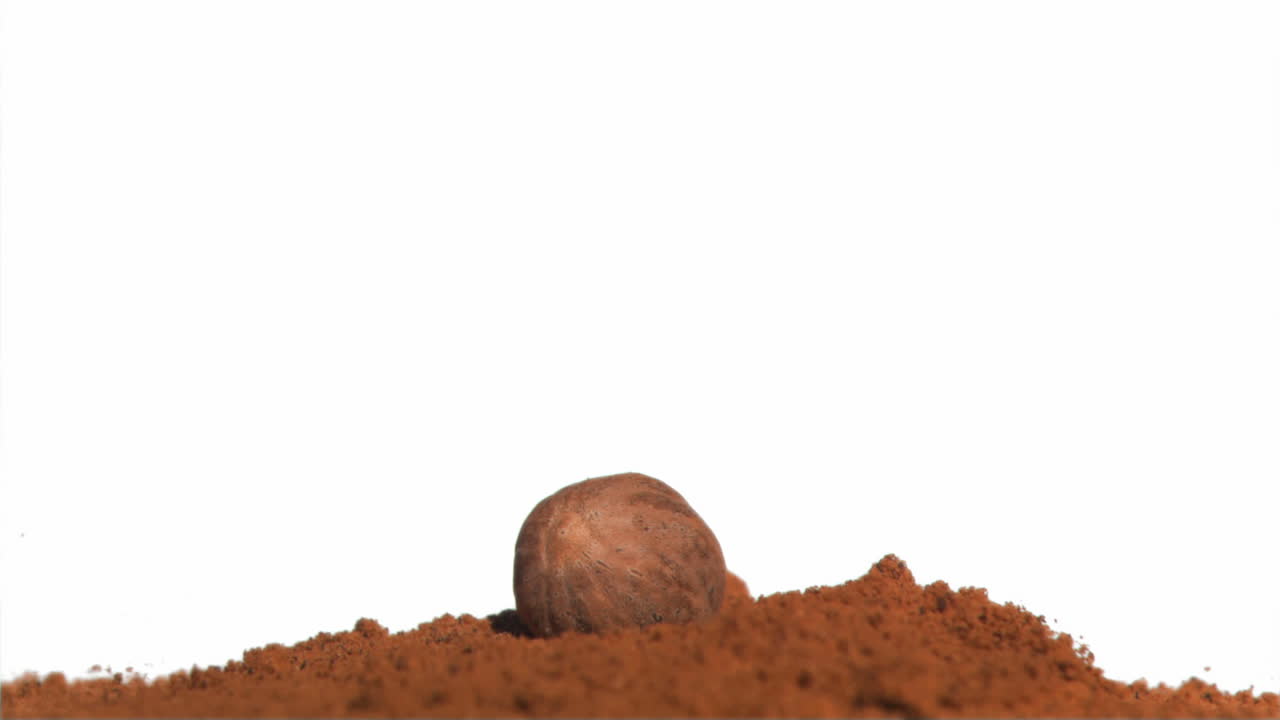 la nuez moscada cayendo en cámara súper lenta en un montón de polvo