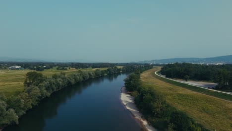 aerial view of sava river bend with tree line and golden grassland in sunlight