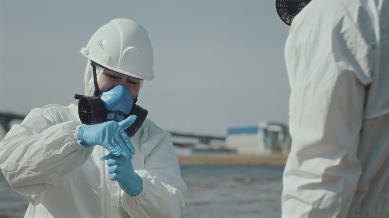 Two Ecologists in Protective Uniform Collecting Seaweed