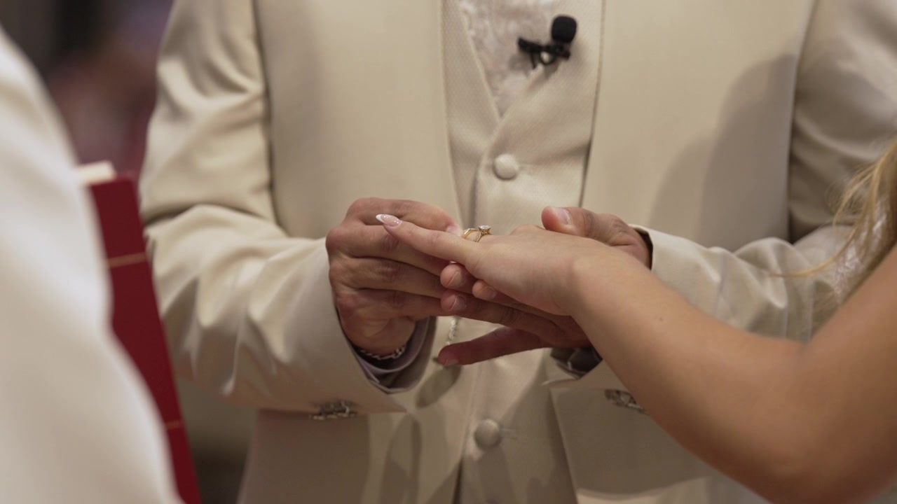 Close up of a groom placing a wedding ring on the bride’s finger during the ceremony