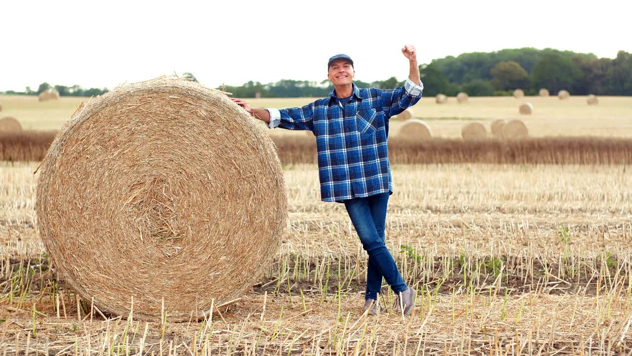 웃는 농부 는  을 굴리고 농장 에서 몸짓 을 하고 있다