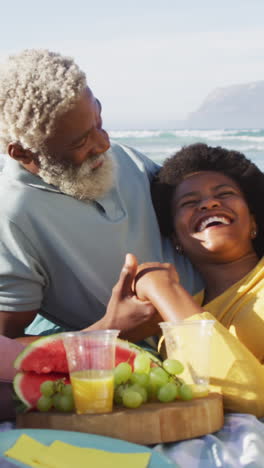 happy african american couple having picnic on sunny beach
