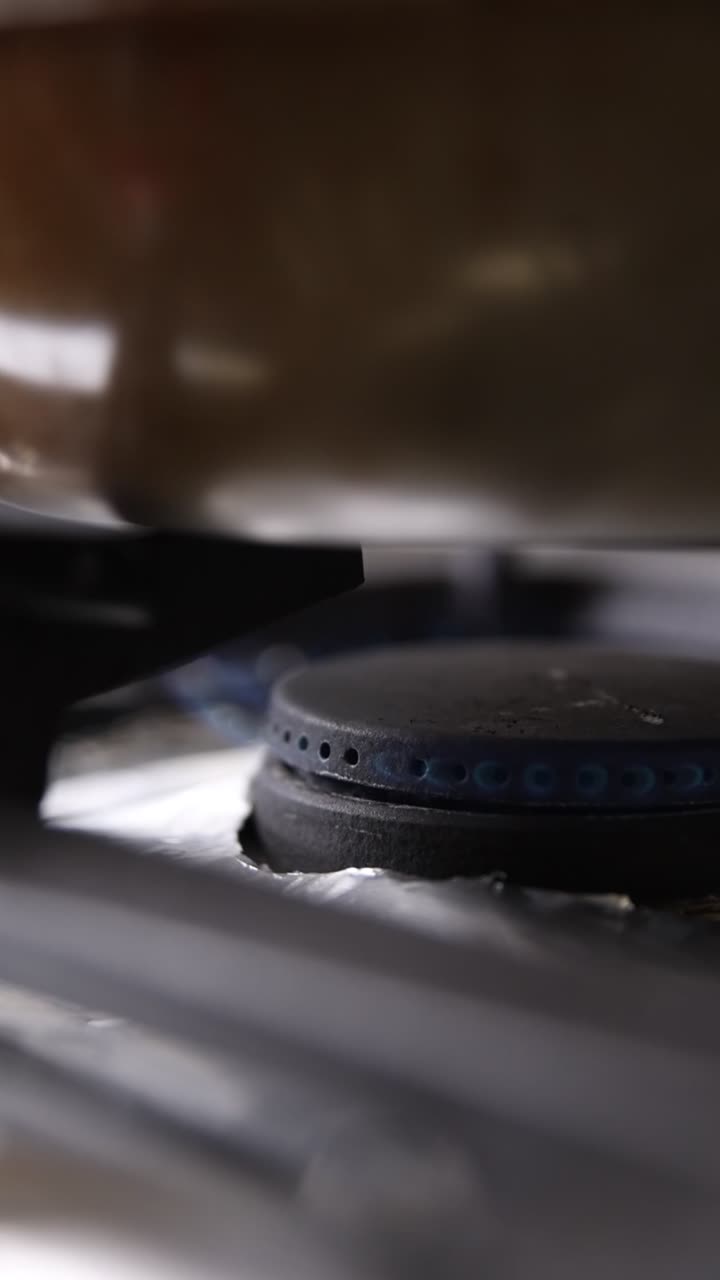 Close Up of Gas Stove Burner Igniting with Blue Flame