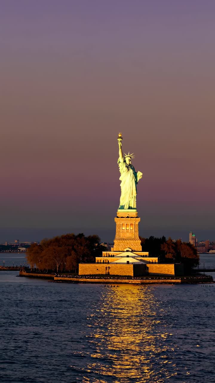 Sunset video still of the Statue of Liberty from a low angle, capturing its majestic silhouette