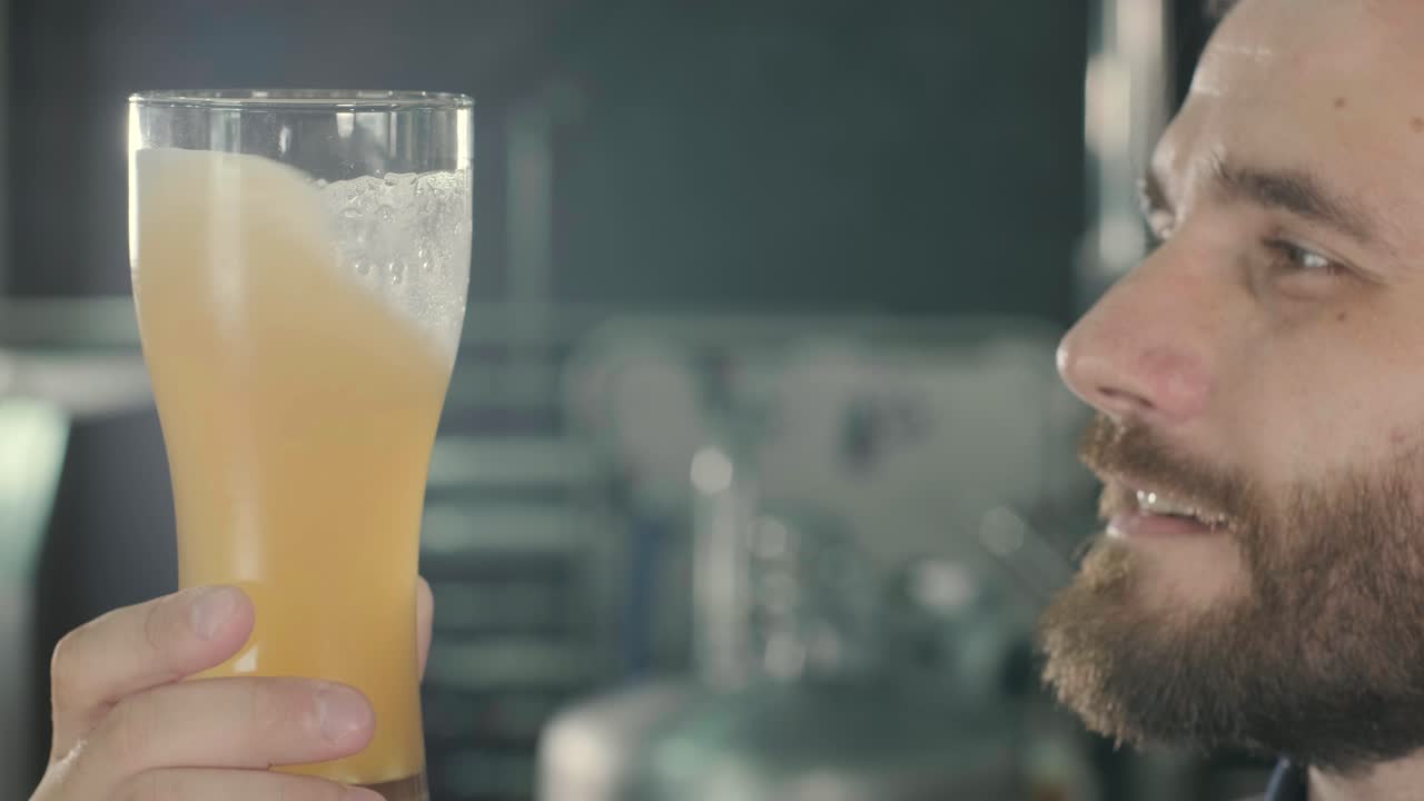 un joven cervecero con un delantal de cuero está probando cerveza en una cervecería moderna