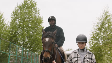 man riding a borwn horse outdoors