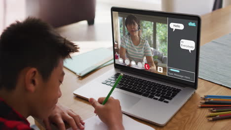 chico asiático haciendo la tarea y teniendo una videollamada con la maestra en la computadora portátil en casa