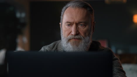 Senior man working computer cabinet. Old businessman using laptop home.