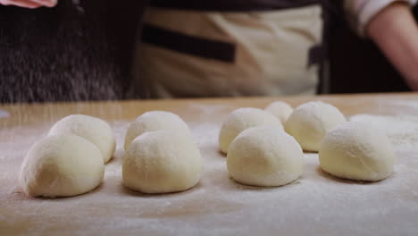 The-baker-rolls-out-the-dough-for-buns-on-the-board.-Working-in-a-bakery.-4k-video