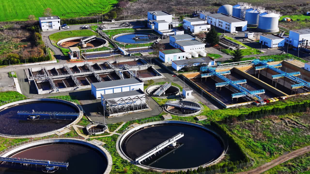 Multiple industrial tanks, silos, and buildings for water purification in daylight. Comprehensive aerial view of modern wastewater treatment station