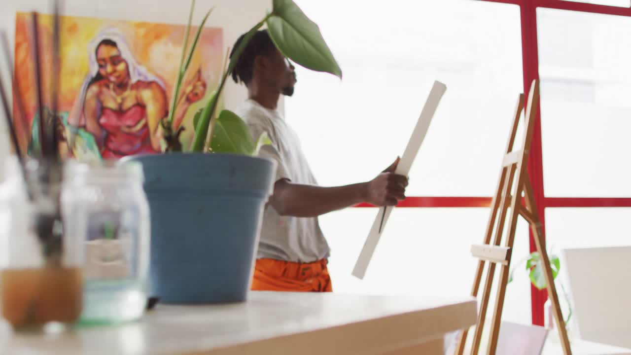African american male painter putting canvas on easel in artist studio