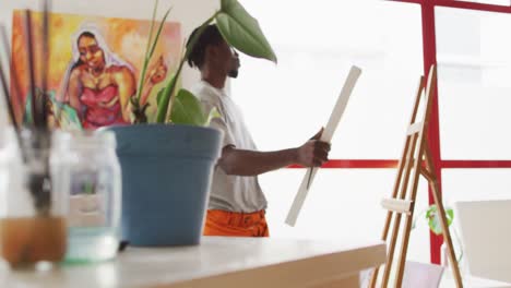 african american male painter putting canvas on easel in artist studio